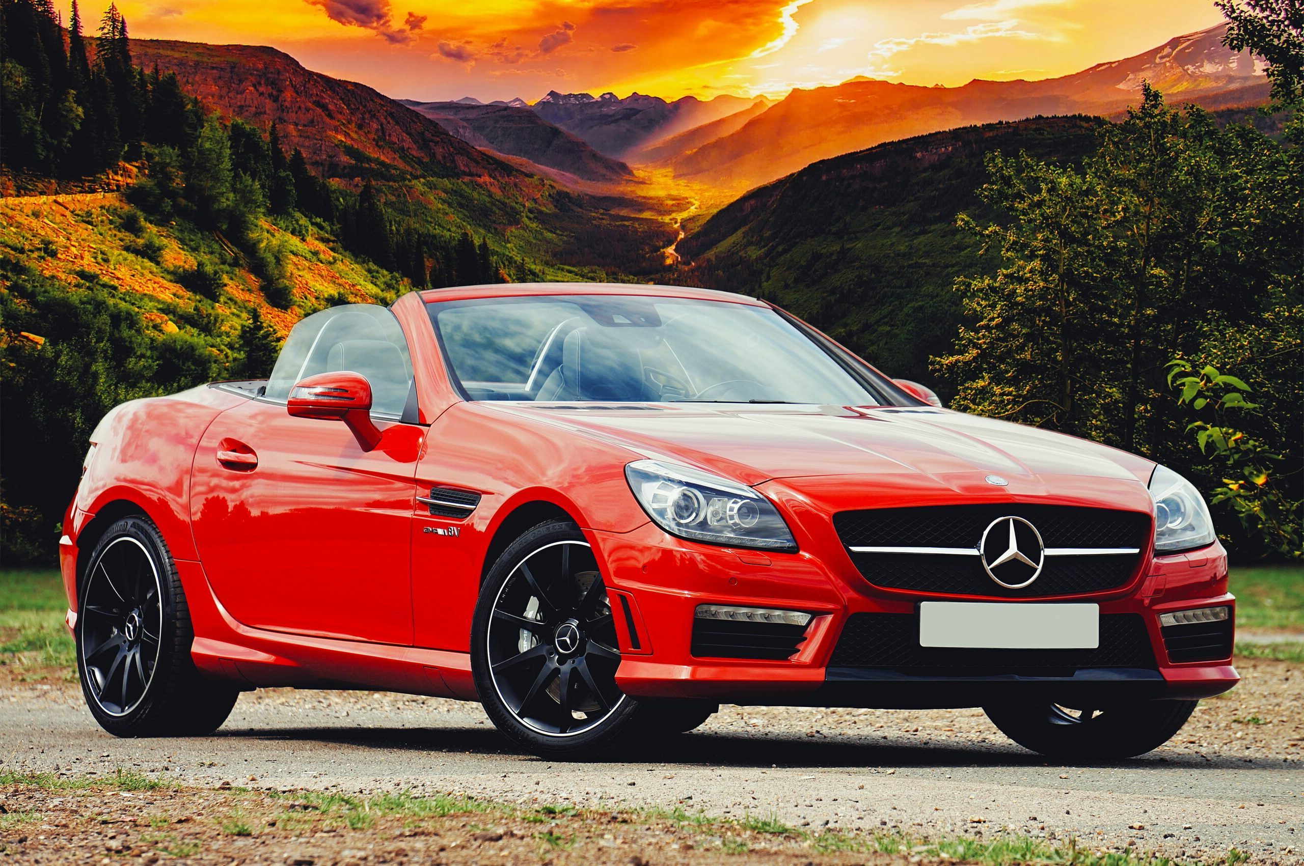 Stunning red Mercedes Benz convertible parked against a breathtaking Scottish sunset backdrop.