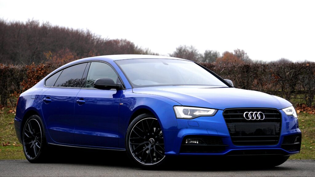Elegant blue luxury car parked outdoors against a natural backdrop.